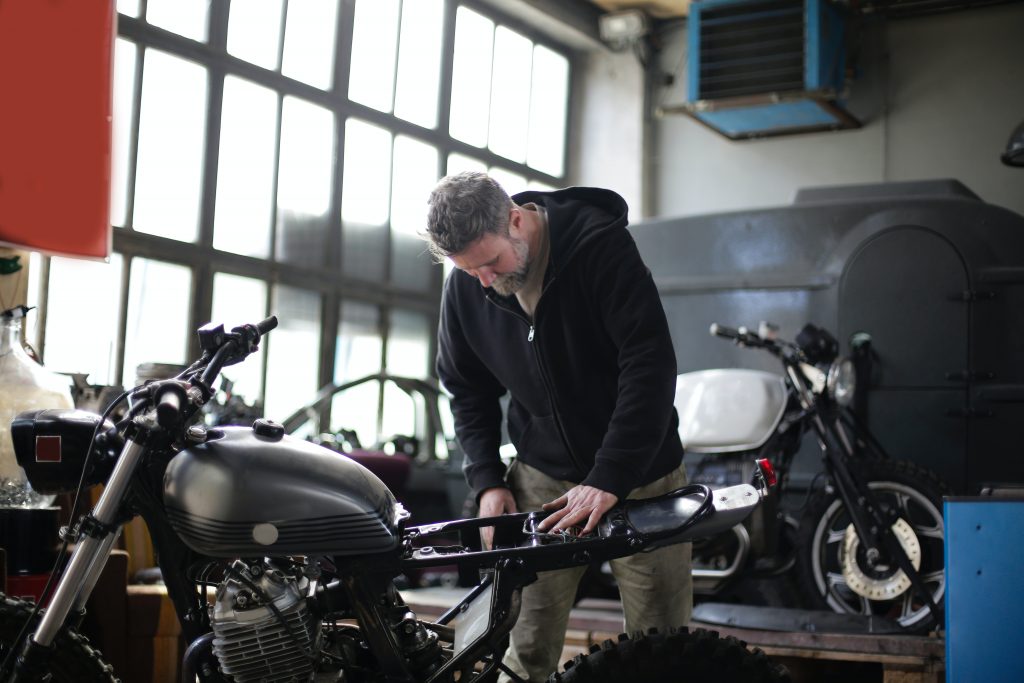 serious adult male mechanic repairing motorbike in garage 3855224